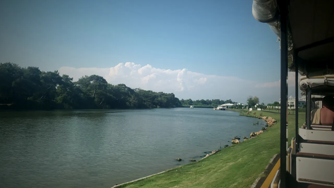 Fahrt mit der Anlagenbahn am Fluss entlang zum Strand, Schilf und Golfplatz
